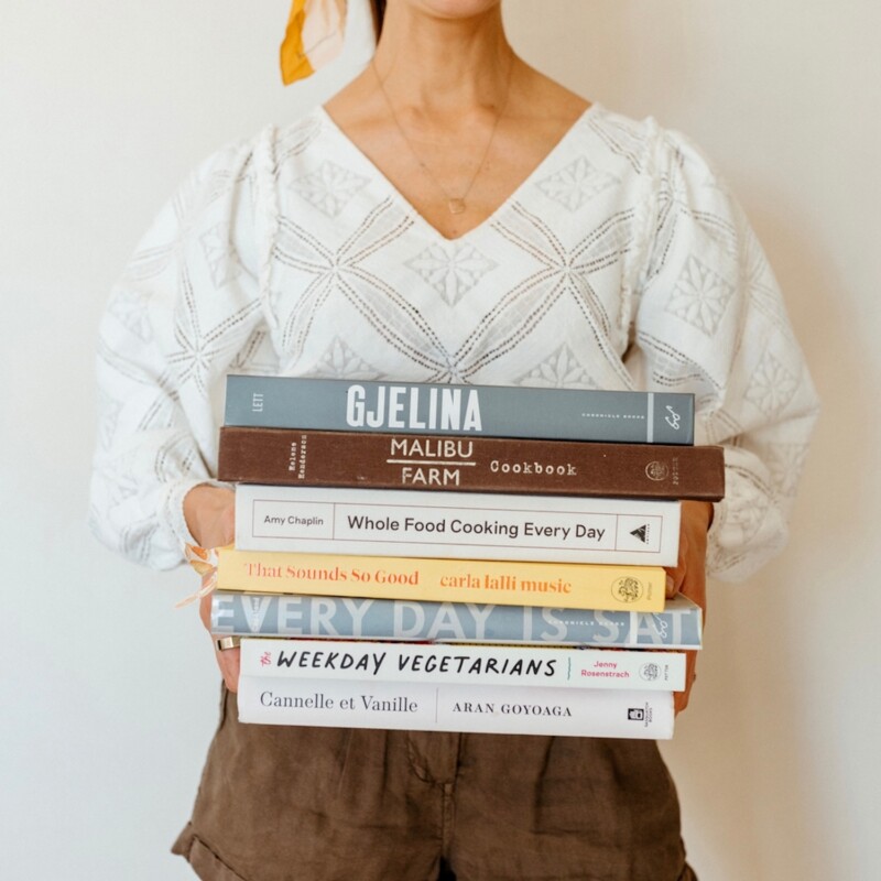 Woman holding stack of beautiful cookbooks.