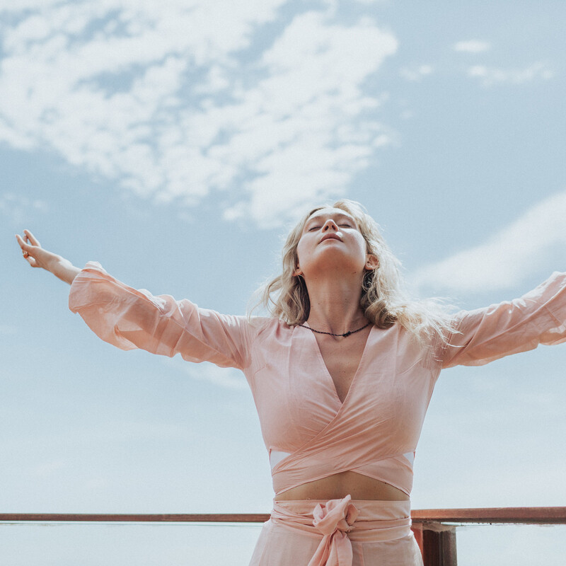 Woman wearing pink dress with arms raised_women and testosterone