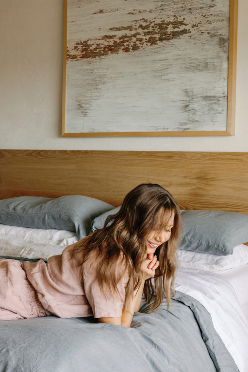 Woman laughing on bed thinking about setting social media boundaries.