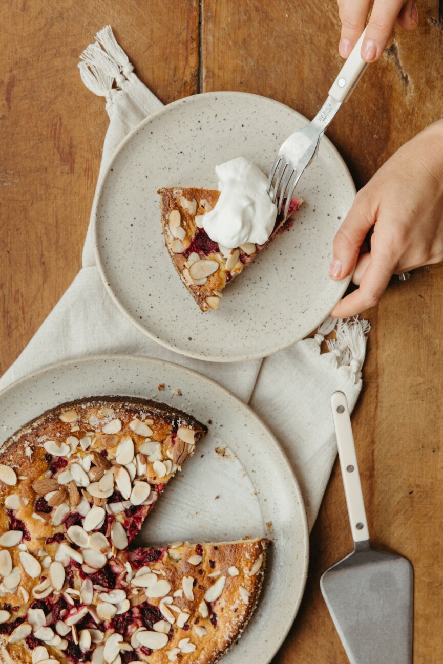 fork taking a bite of a grain free lemon raspberry cake with whipped cream on top