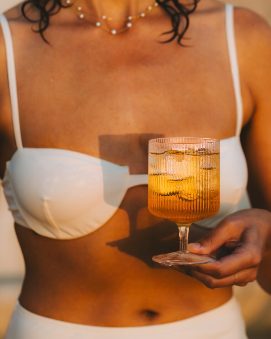 woman holding cocktail in swimsuit