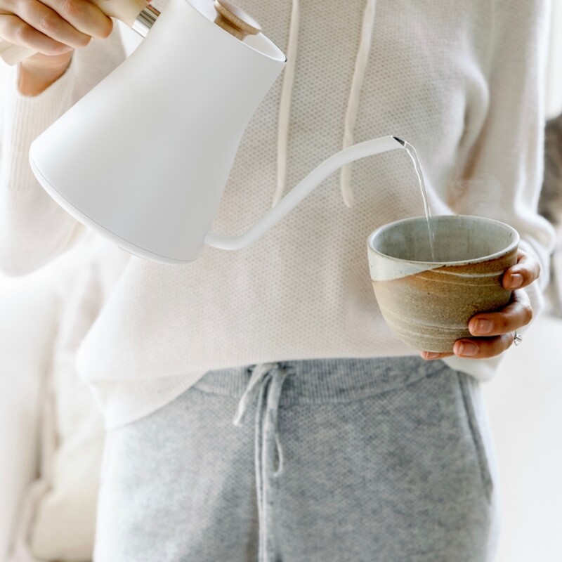 Pouring water from white electric tea kettle.