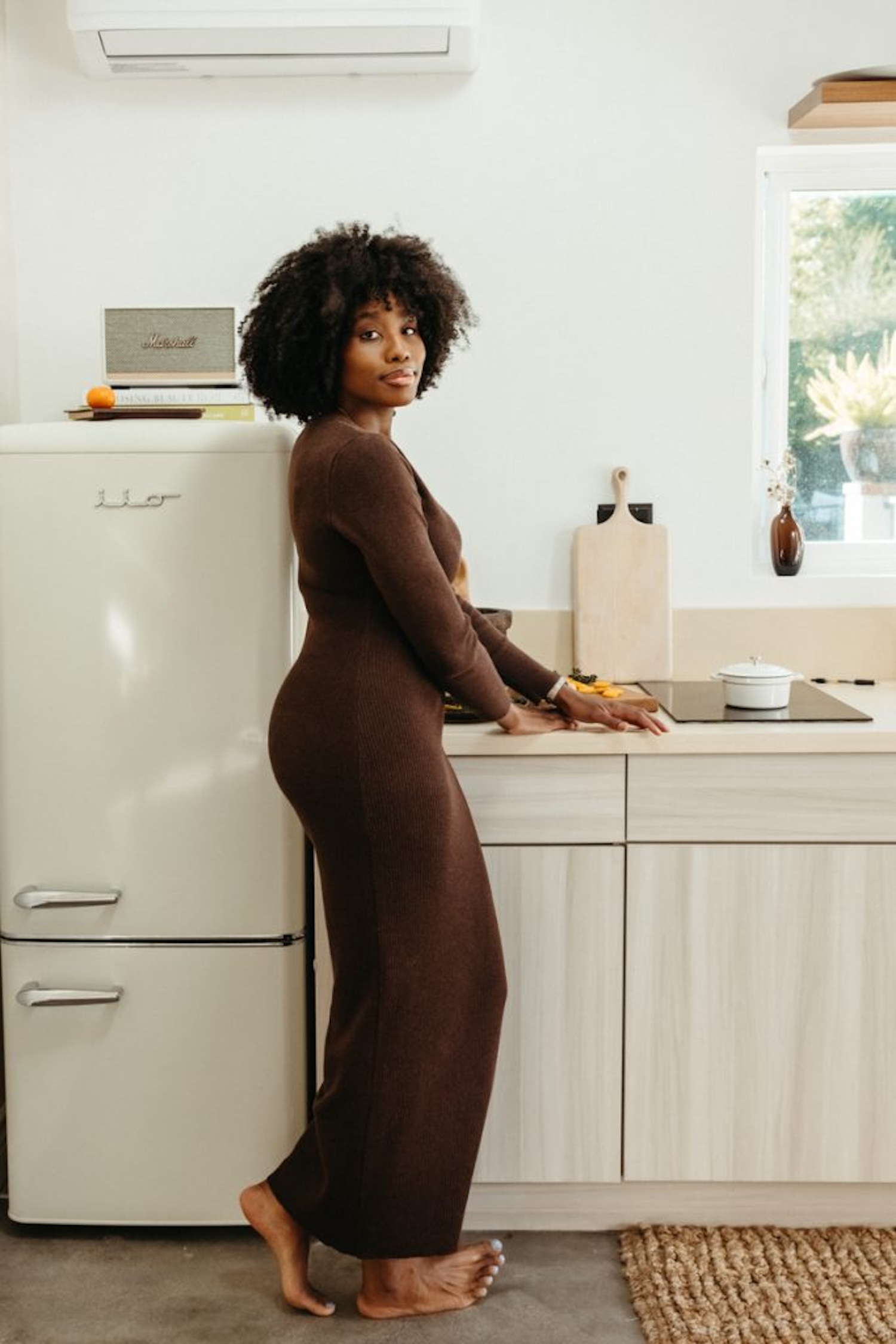 Woman wearing brown dress in kitchen.