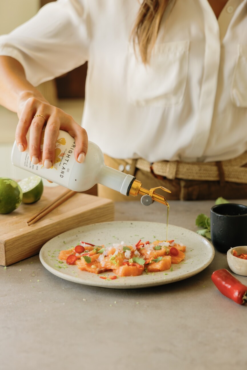 camille styles pouring olive oil on salmon crudo