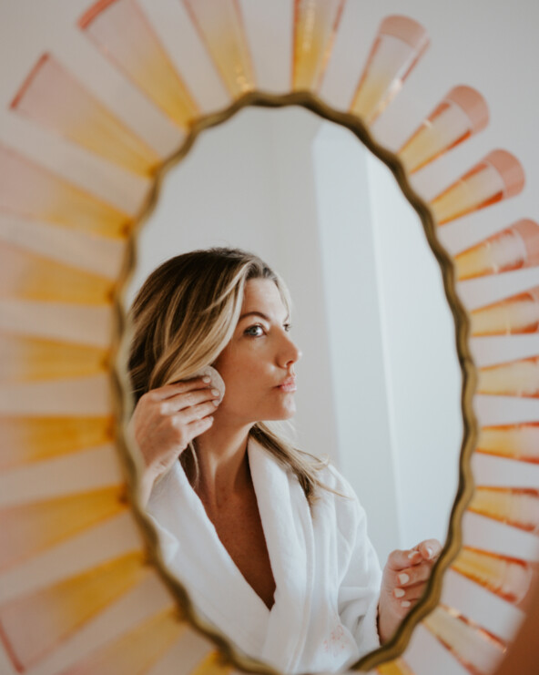 Woman applying makeup in mirror.