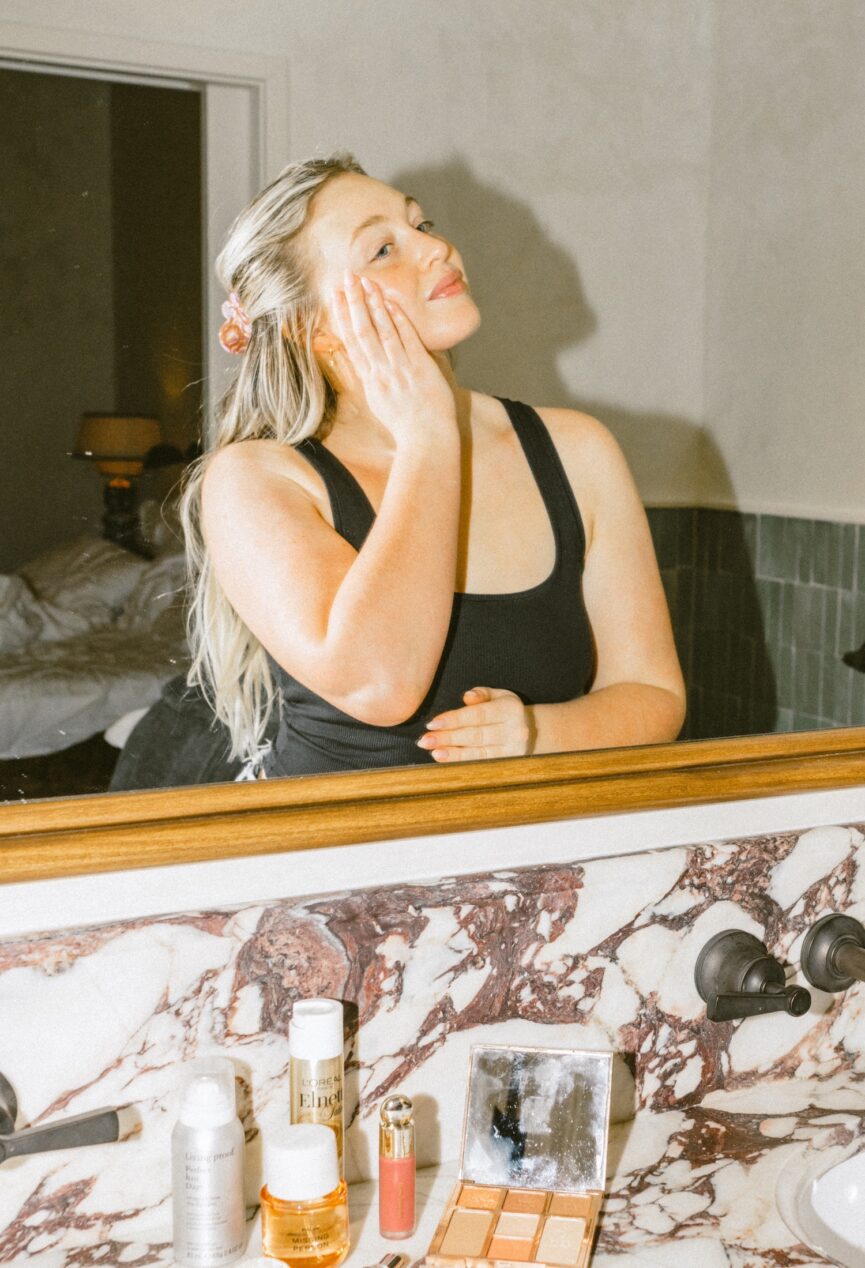 Woman applying olive oil for skin in the mirror.