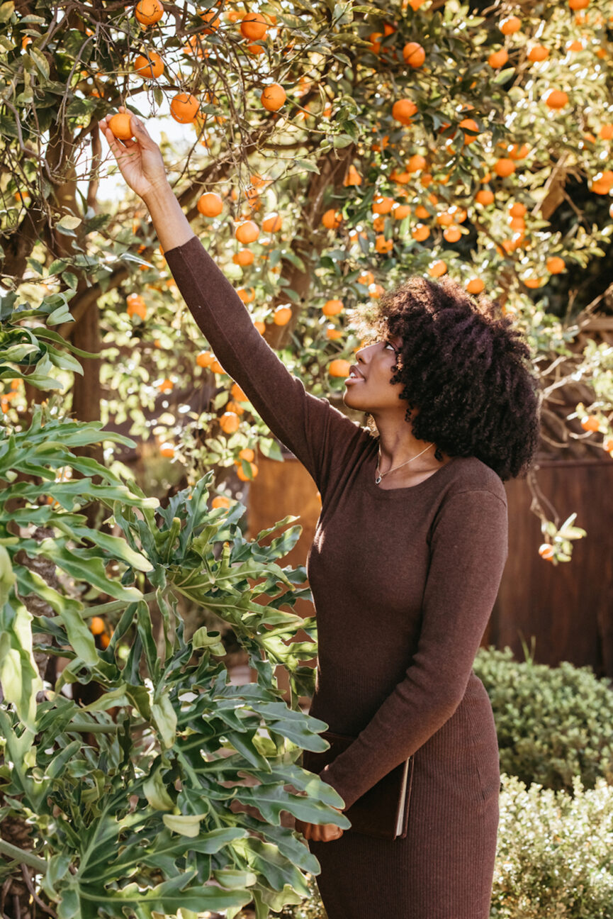 Woman picking oranges outside.