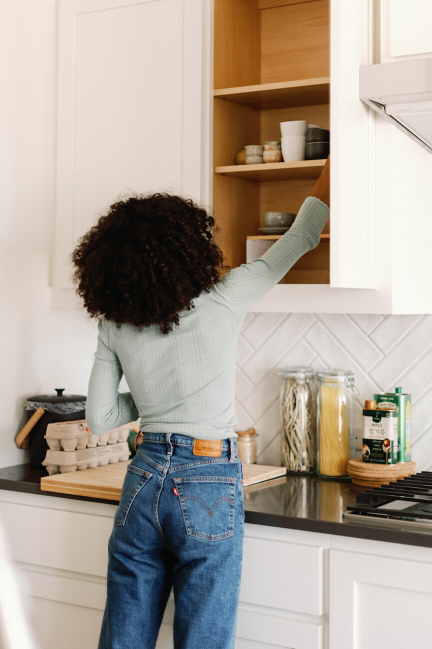 Woman reaching in cabinet.